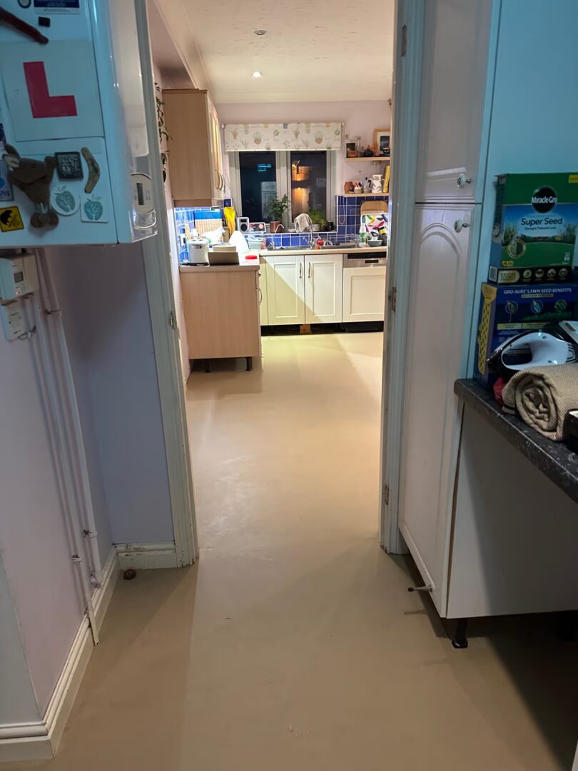 Smooth levelled subfloor running from a hallway through a doorway into a kitchen with units still in place