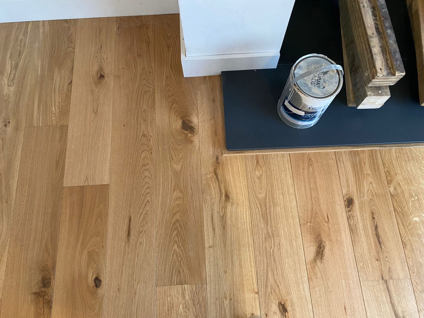 Oak plank flooring fitted neatly around a dark slate-style fireplace hearth, with a matching oak edge trim.