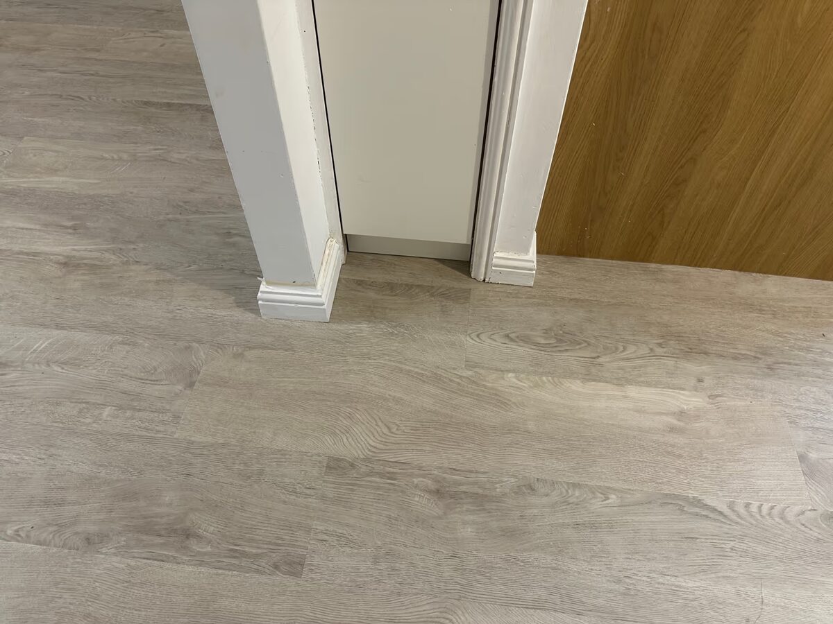 White Oak flooring fitted around white door architraves, next to a cupboard door and an oak-effect panel