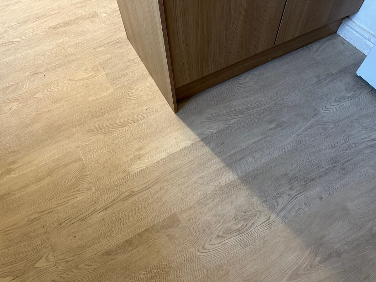 Sunlight and shadow falling across White Oak flooring beside the end panel of a kitchen unit